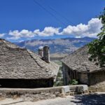 A stone house with a sloping roof made of gray tiles