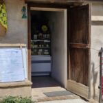 In the open door of the small shop you can see a counter with jars on it.