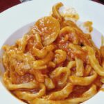 Thick spaghetti with tomato sauce in a white plate.