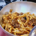 Grube spaghetti z mięsem w srebrnej metalowej misce.