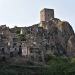 On a grassy hill stand the ruins of a small stone city.