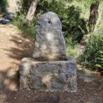 A small old stone fountain stands on a stone path.