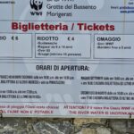 White information board with ticket prices in black font, a drawing of a panda and text in Italian.