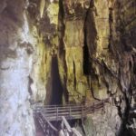 A wooden bridge runs along the rock wall in the cave.