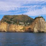 A rocky island slightly overgrown with vegetation protrudes from the sea.